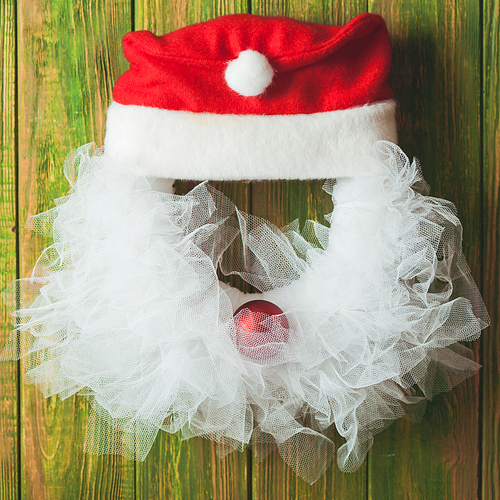 Christmas wreath like Santa head from lace and red bauble on the wooden door