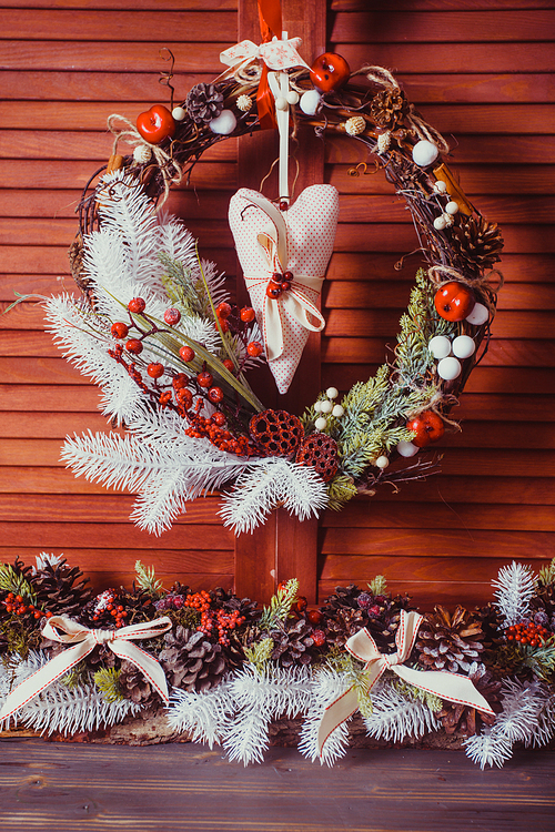 Christmas wreath on the wooden wall. Red and white elements, textile heart hangs