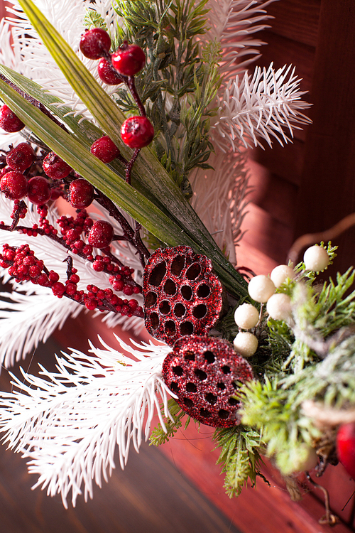 Christmas wreath on the wooden window. Red and white elements close up