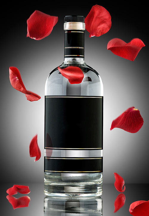 A photo of luxury alcohol bottle with falling rose leaves.