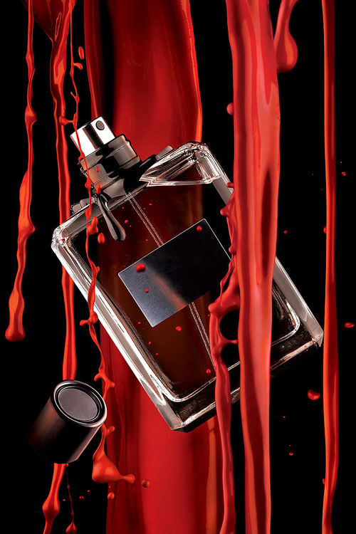 A stylish view of a bottle of male perfume and flowing red paint.