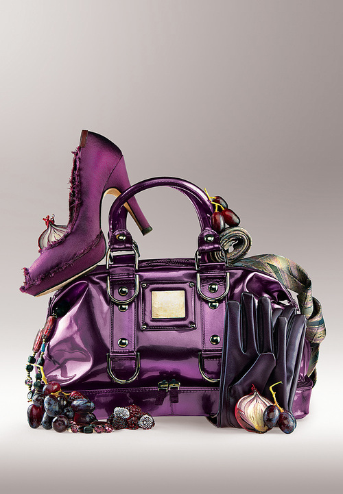 Violet shoe on a purse with jewelry and gloves.