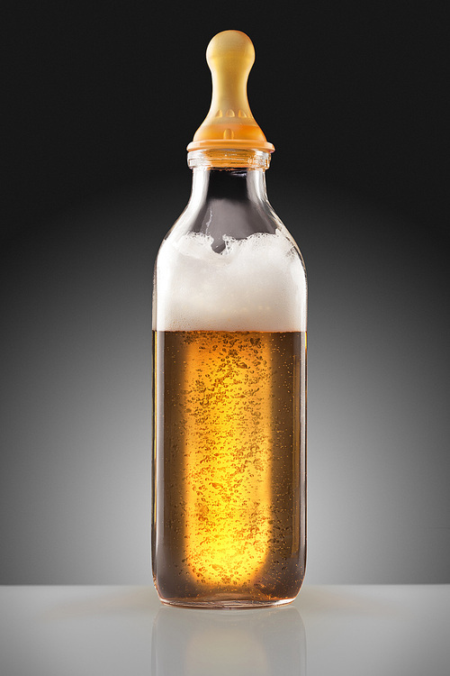 A feeding bottle with nipple full of beer as a milk replacement for babies.