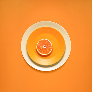 Creative concept photo of kitchenware, painted plate with food on it on orange background.