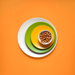Creative concept photo of kitchenware, painted plate with food on it on orange background.