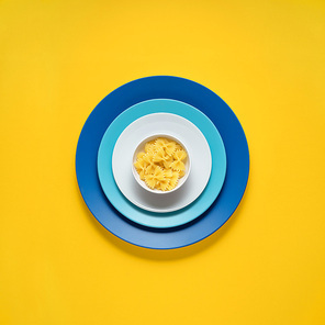 Creative concept photo of kitchenware, painted plate with food on it on yellow background.