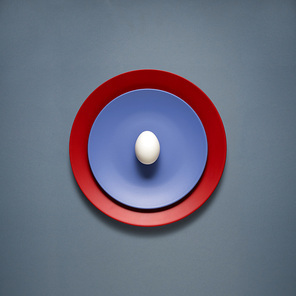 Creative concept photo of kitchenware, painted plate with food on it on grey background.