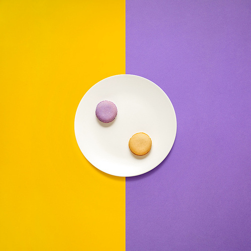 Creative concept photo of kitchenware, painted plate with food on it on yellow purple background.
