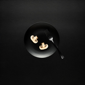 Creative concept photo of kitchenware, painted plate with food on it on black background.