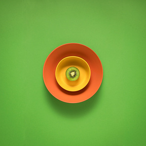 Creative concept photo of kitchenware, painted plate with food on it on green background.