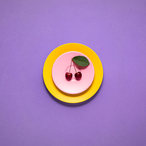 Creative concept photo of kitchenware, painted plate with food on it on purple background.
