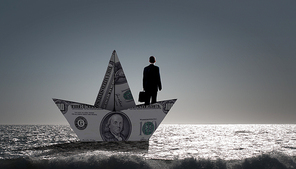 Successful businessman sailing on dollar boat in financial sea