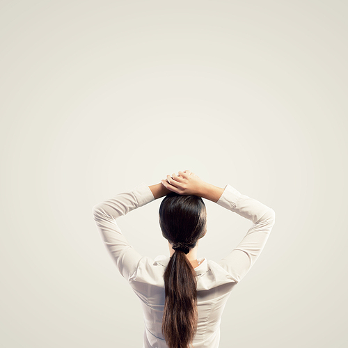 Image of young woman standing with her back with arms above head. Place for text