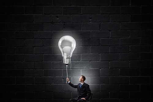 Businessman with bulb on rope representing bright idea