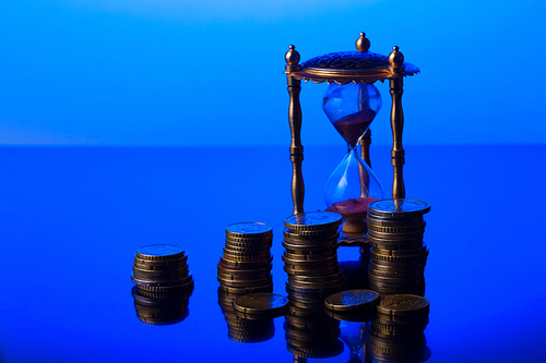 Time is money concept - hourglass with piles of euro coins
