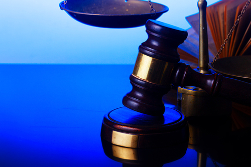 Law and justice concept - law gavel with scale on blue background close up