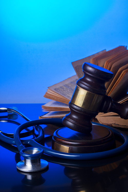 Wooden law gavel with stethoscope and book - medical law and justice concept