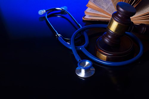 Wooden law gavel with stethoscope on blue with copy space - medical law and justice concept