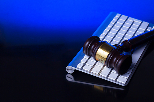Wooden law gawel on computer keyboard, internet auction concept, futuristic blue background