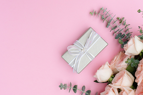gift or present box and flowers on pink table from above, flat lay scene