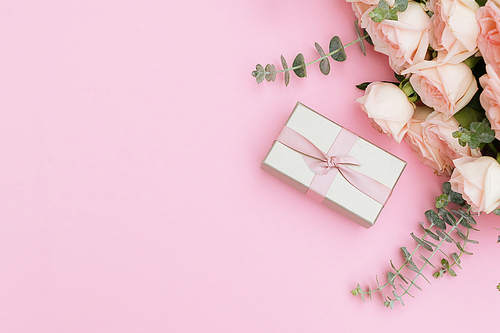 gift or present box and flowers on pink table from above, flat lay frame