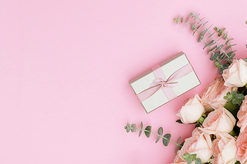 gift box and flowers on pink table from above, flat lay frame