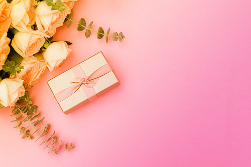 gift or present box and flowers on pink table from above, flat lay frame, toned