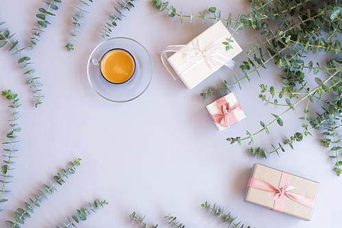 Green leaves with gift boxes with coffee on blue table from above with copy space, flat lay scene