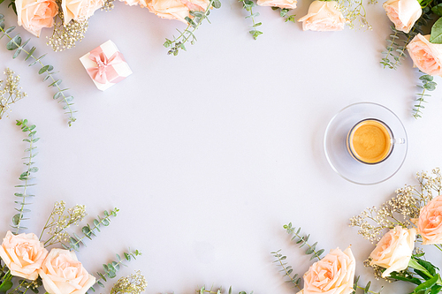 Cup of coffee with gift or present box and flowers on blue background from above, copy space
