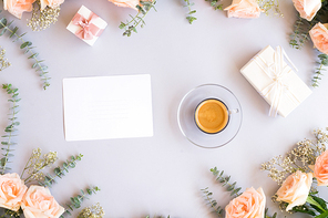 Cup of coffee with gift or present box and flowers on blue table from above, copy space on blank paper card