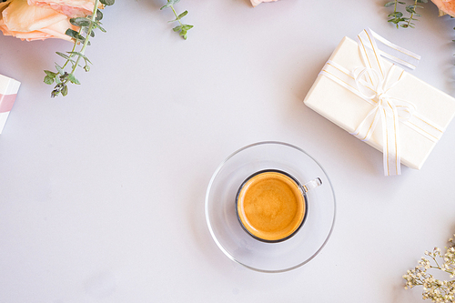 Cup of coffee with gift or present box and flowers on blue table from above