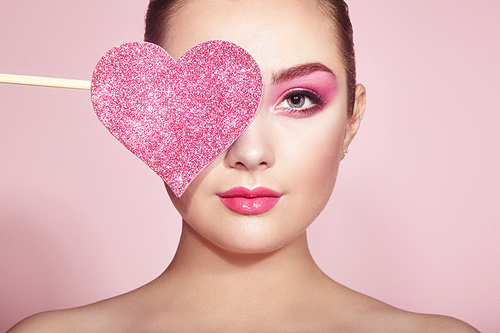 Beauty Young Fashion model Girl with Symbol Valentine Heart shaped in hand. Love. Beautiful young Woman with Holiday Makeup. Valentines Day gift