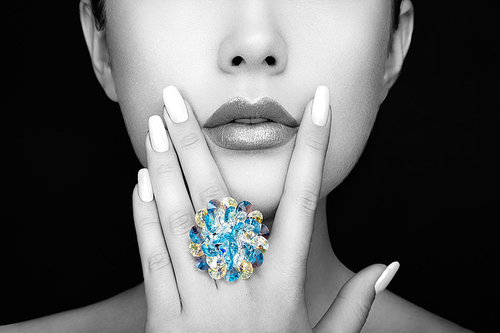 beauty fashion woman lips with natural makeup and white nail polish. gloss lipstick. beauty girl face close up.  lips, manicure, make up. ring with precious stones, jewelry