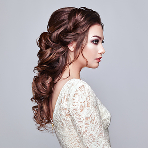 Brunette Woman with Long and shiny Curly Hair. Beautiful Model Lady with Curly Hairstyle. Care and Beauty Hair products. Care and Beauty of Hair