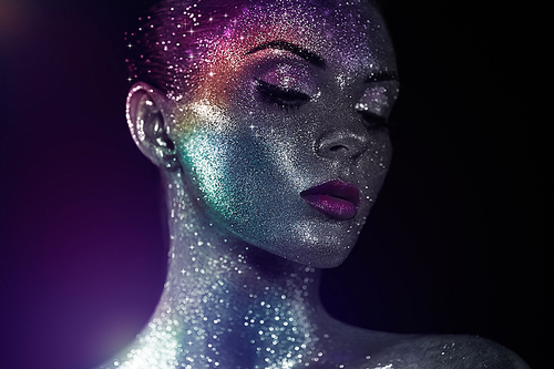 Portrait of Beautiful Woman with Sparkles on her Face. Girl with Art Make-Up in Color Light. Fashion Model with Colorful Makeup