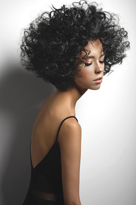 Fashion studio portrait of beautiful woman in black dress with afro curls hairstyle. Fashion and beauty
