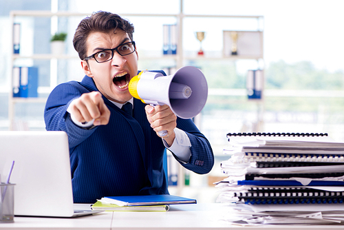 Angry aggressive businessman with bullhorn loudspeaker in office