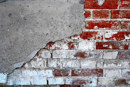 Abandoned brick wall half coverd with cracked plaster, shot with copyspace