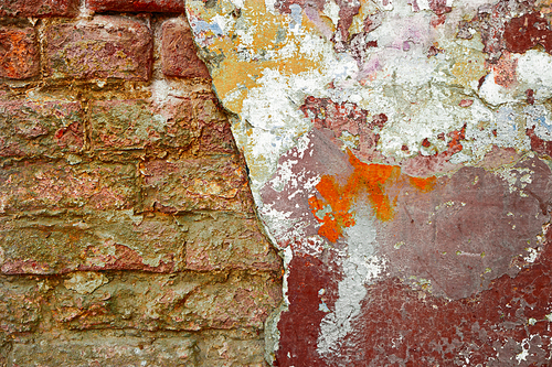 Half weathered brick wall a lot of copy space. Cracked wall. Aged architecture detail.Grunge brick wall half plastered. Half-painted weathered brick wall with copy-space.