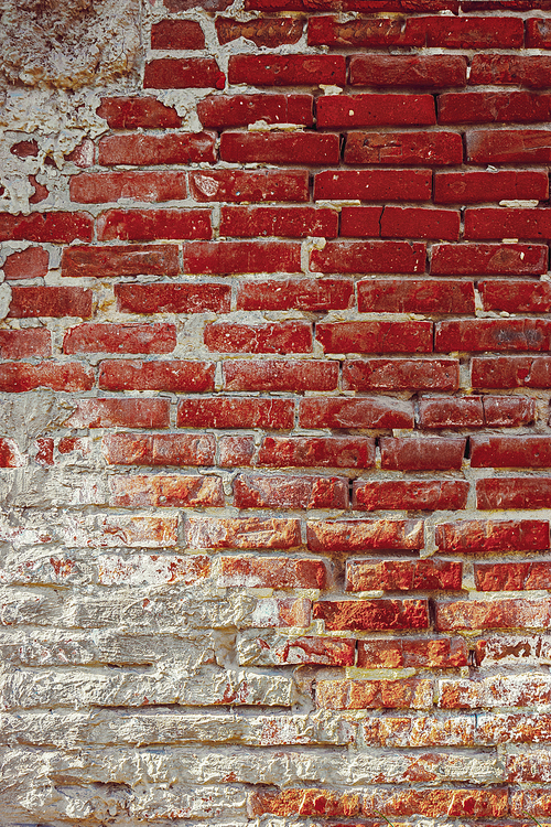 Ancient red brick wall with plaster on low half, copy space on background.