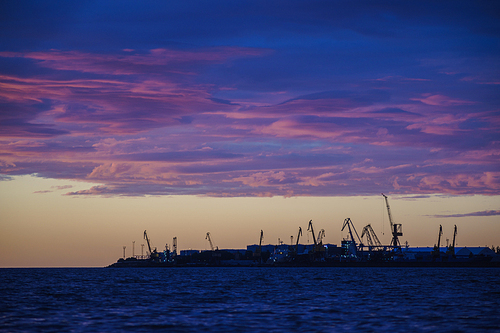 Cargo harbor terminal silhouette by sunset with vivid clouds. Industrial concept