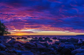 stony coast of Baltic sea by vivid sunset with fiery cloudscape