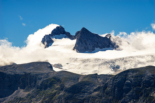 Peaks of Dachstein massif covered by glacier and clouds, Austria