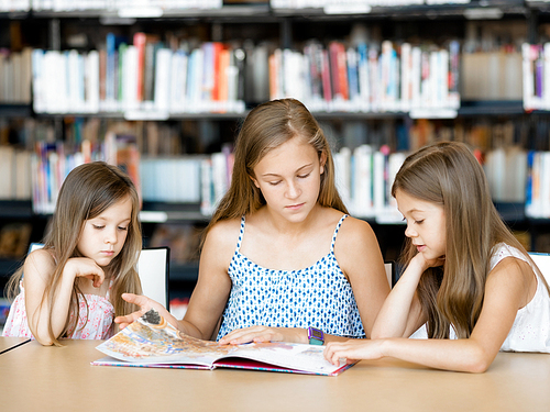 Little girls reading books in library