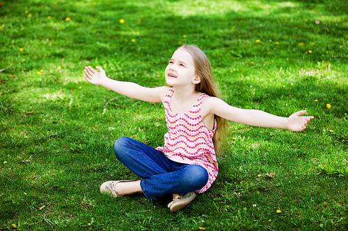 Image of little cute girl sitting on grass in park