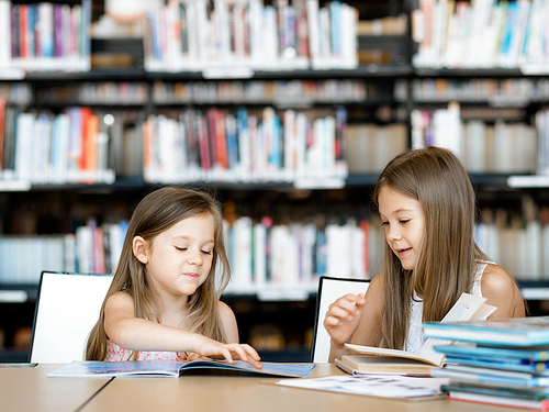 Little girls reading books in library