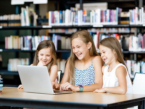 Little girls with a laptop in library
