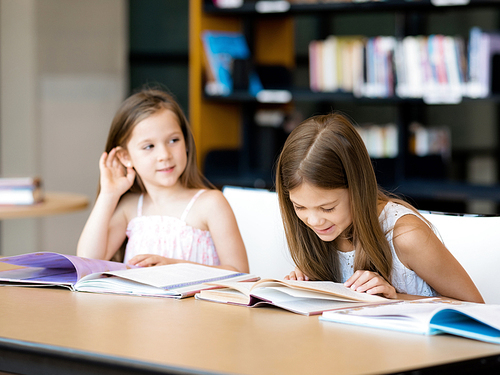 Little girls reading books in library