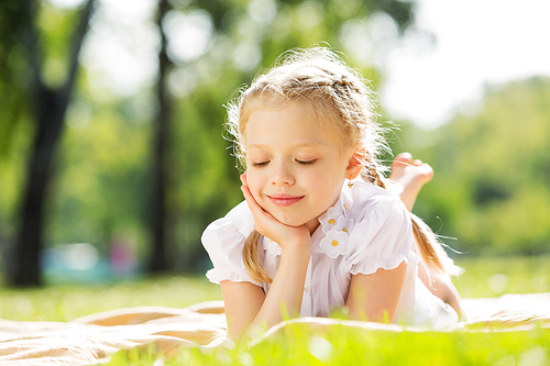 Little cute girl in summer park reading book