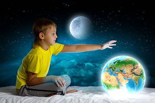 Cute boy sitting in bed and dreaming. Elements of this image are furnished by NASA